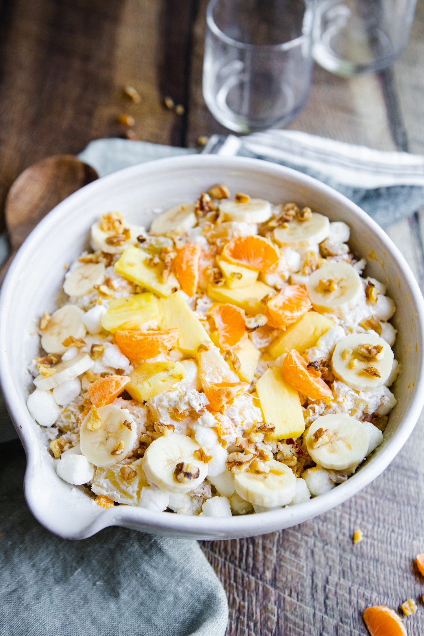 white bowl filled with ambrosia fruit salad made with cool whip and topped with mandarin oranges and bananas 