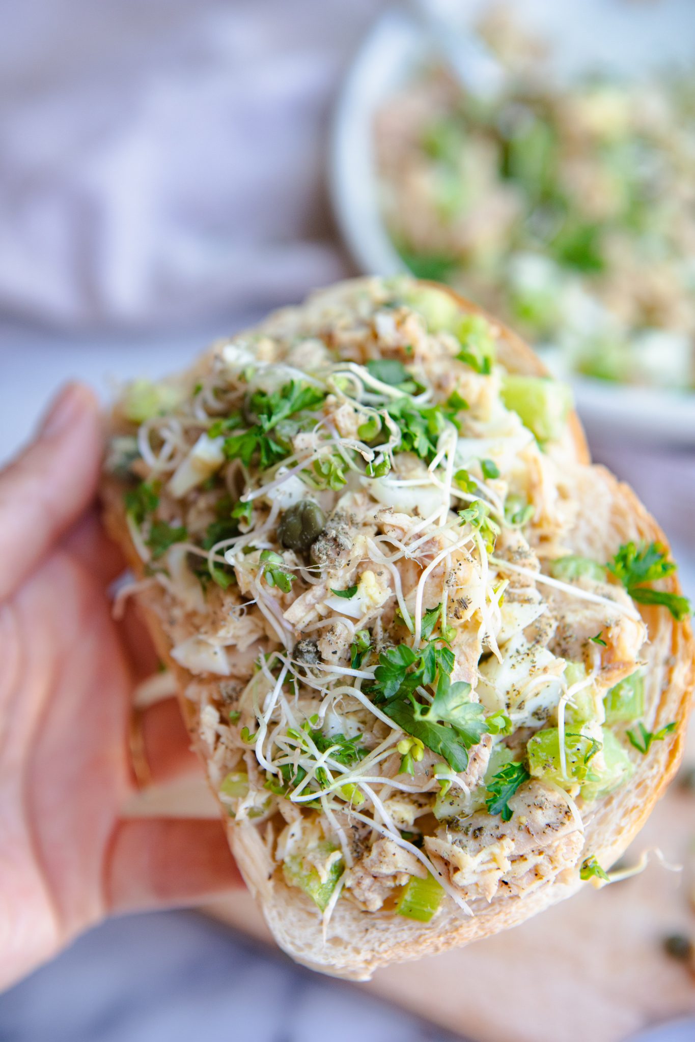 woman holding a piece of toast with tuna salad on top