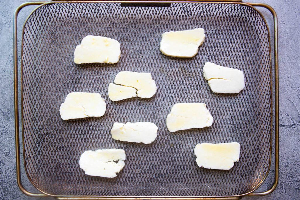 raw halloumi cheese slices on a air fryer basket