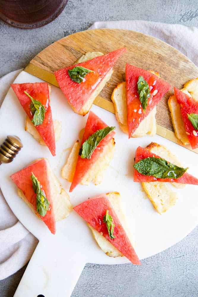 honey drizzled on cheese and watermelon slices garnished with mint