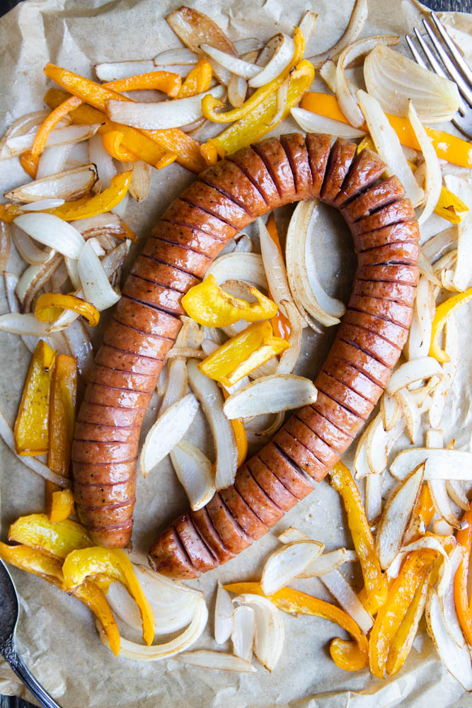 air fryer kielbasa with onions and peppers on a tray lined with parchment paper