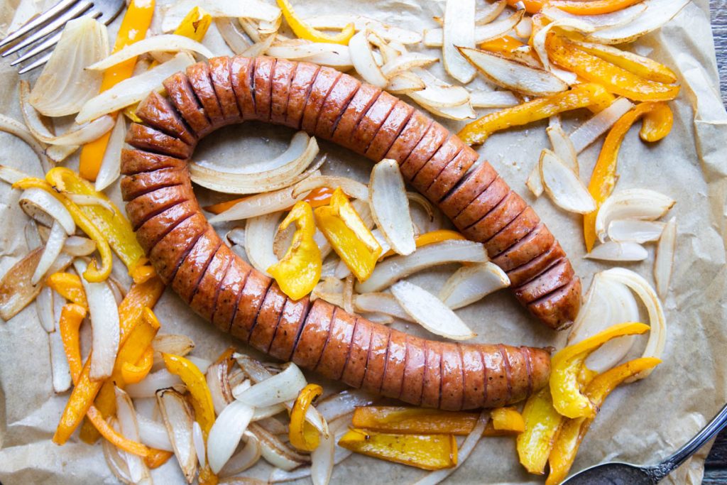 Air fryer kielbasa with peppers and onions on parchment paper