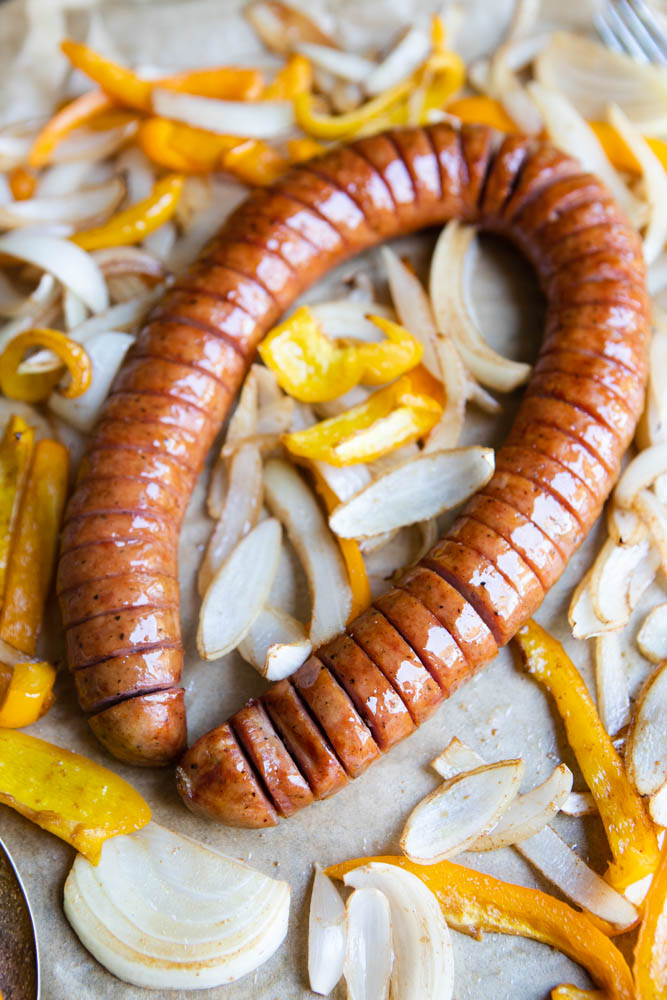 sliced kielbasa surrounded by cooked peppers and onions