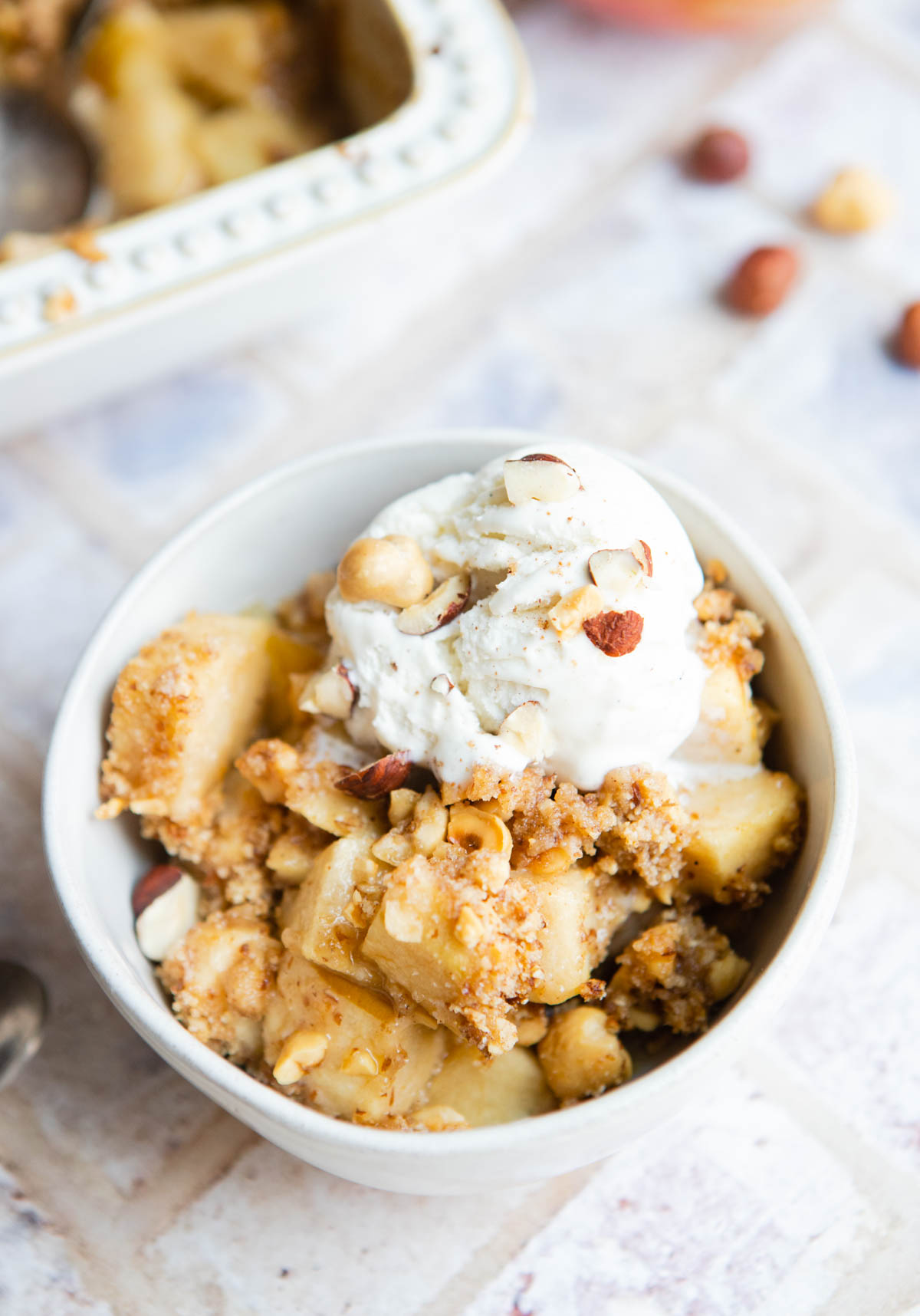 vanilla ice cream scooped on top of a bowl of apple crumble 