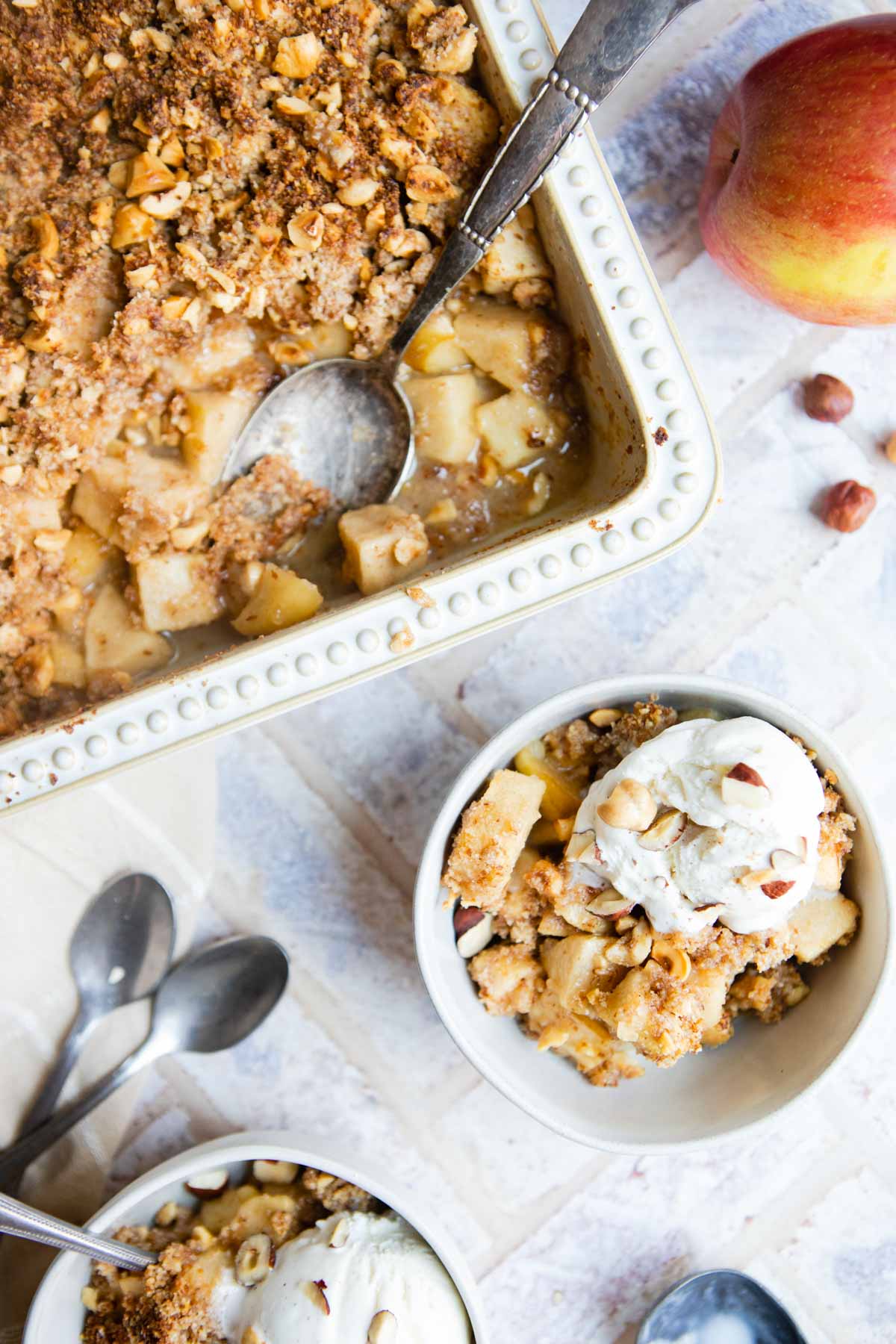 white round bowl and rectangle baking dish filled with apple dessert and topped with ice cream