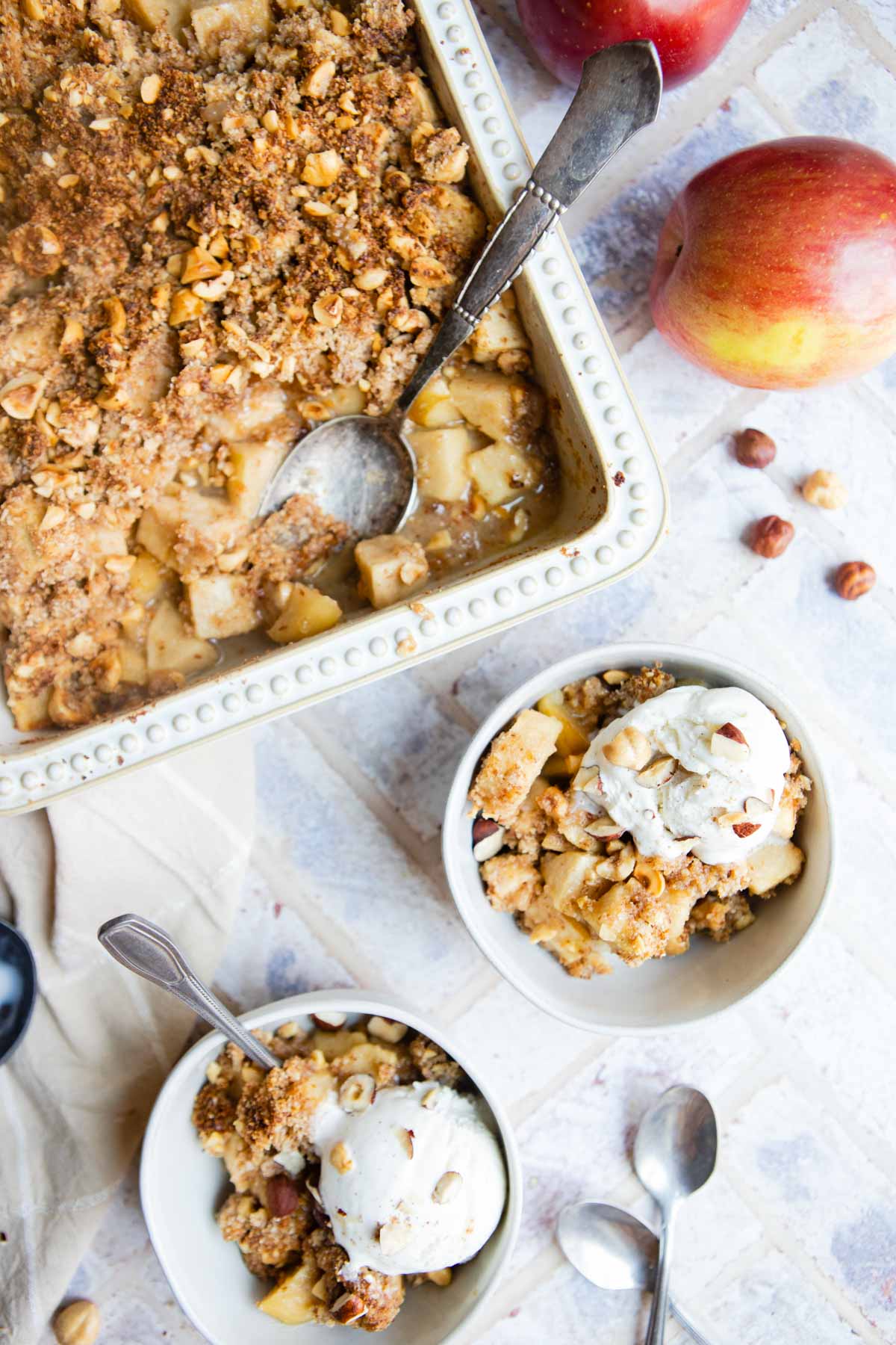 2 white bowls filled with apple dessert topped with vanilla ice cream