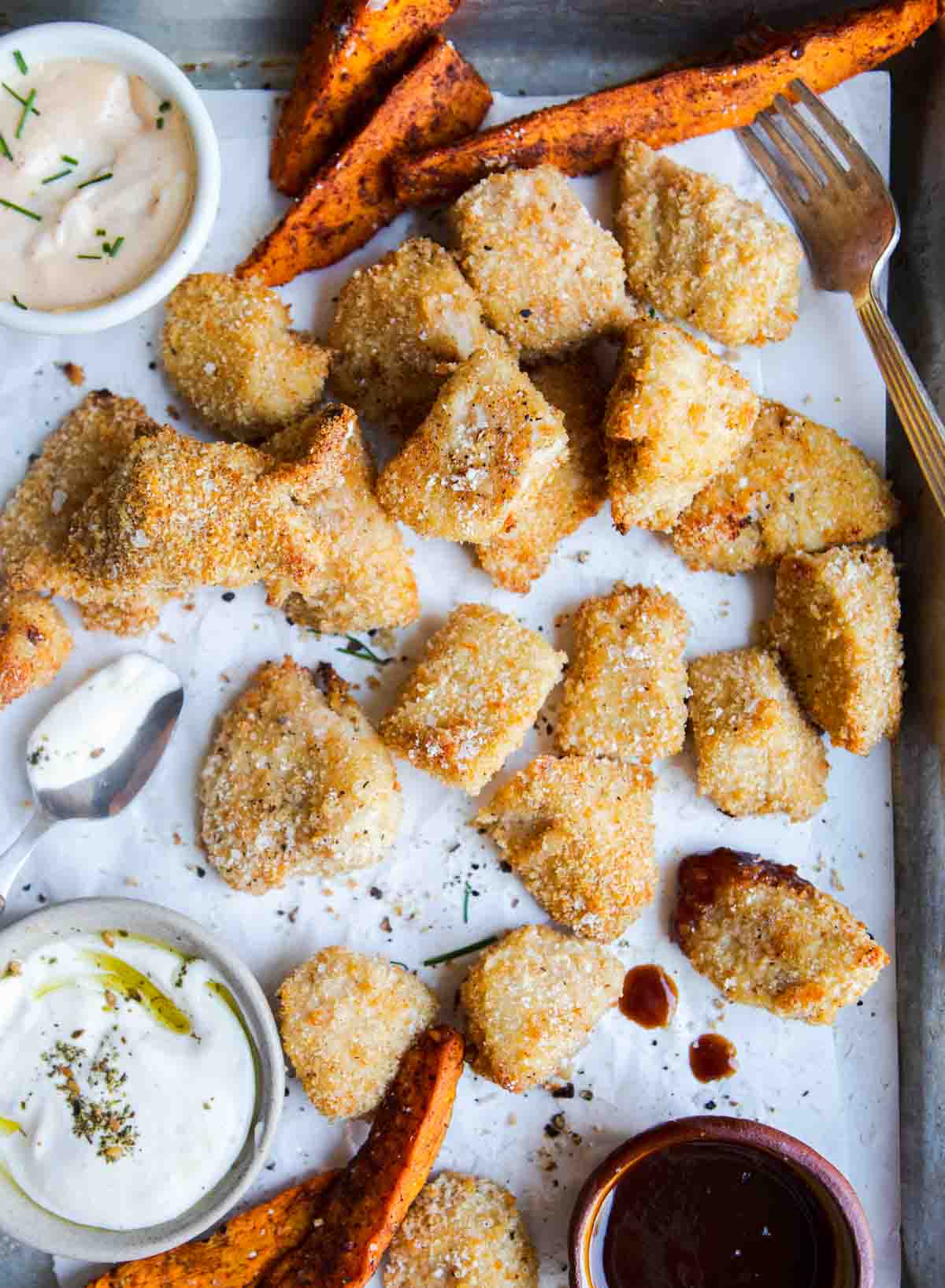 sweet potato fries and air fryer chicken bites on a baking tray with dipping sauces 