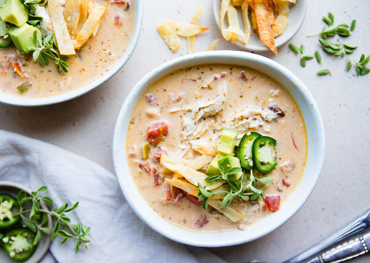 2 bowls of creamy taco soup garnished with homemade tortilla strips and avocado 