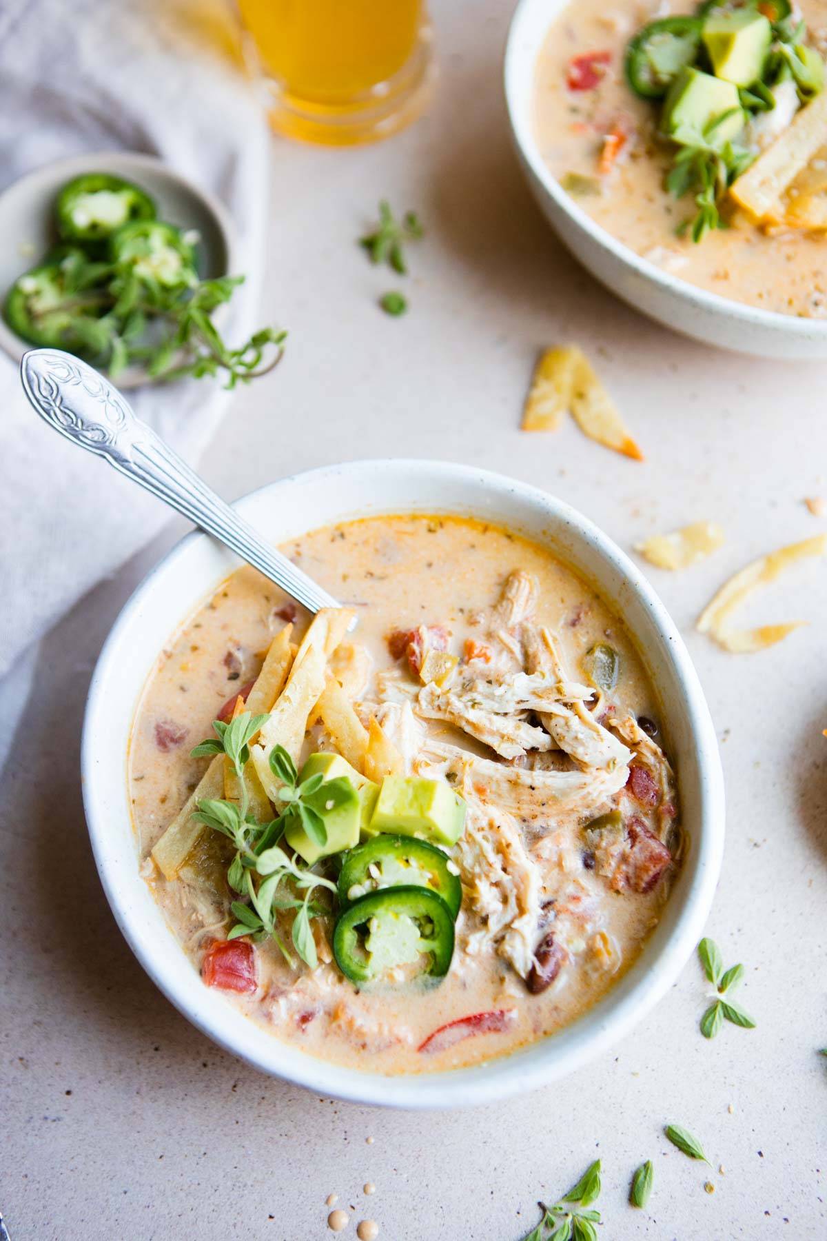 creamy taco soup with shredded chicken in a white bowl topped with garnishes 