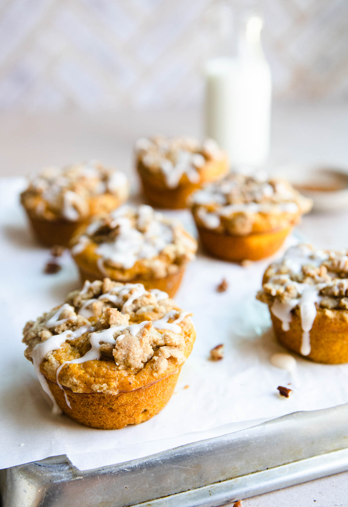 pumpkin banana muffins on white parchment paper with a glass of milk