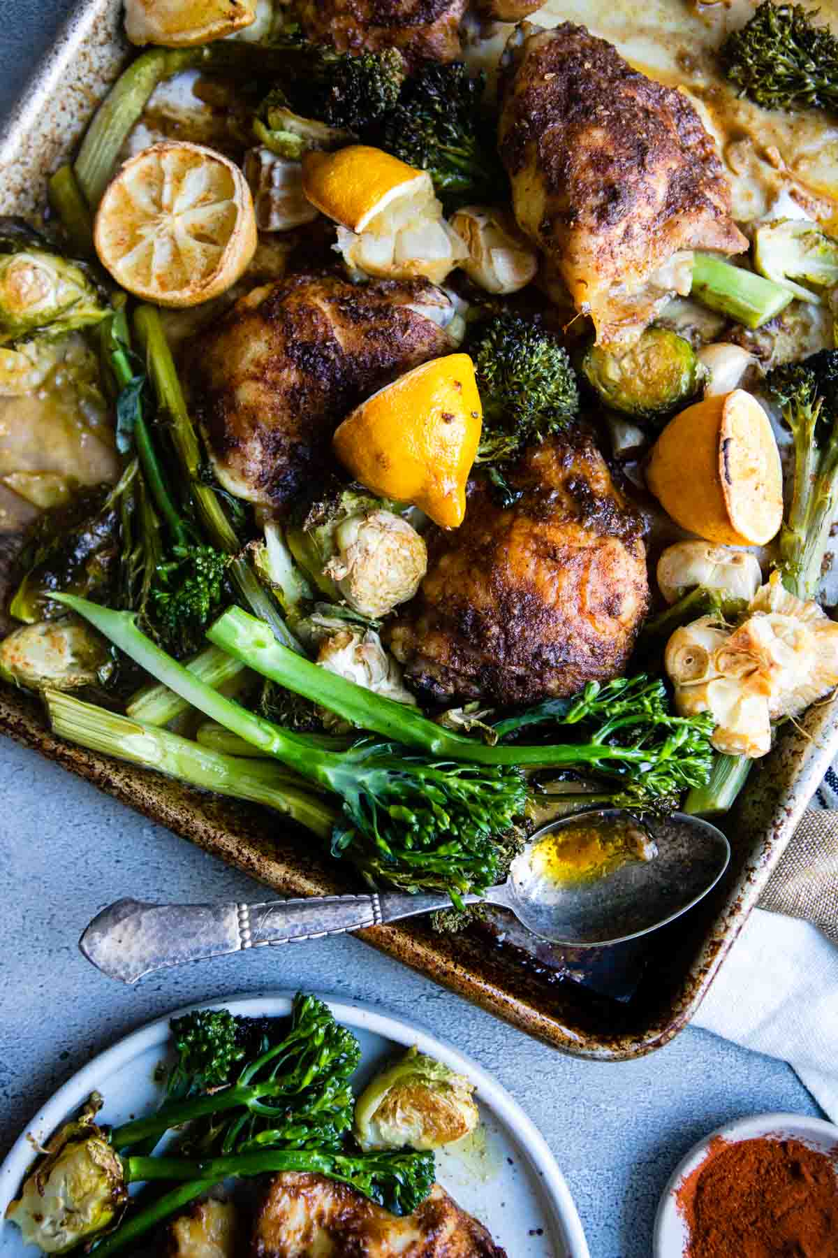 sheet pan filled with a roasted dish of marinated chicken thighs broccolini and brussel sprouts 