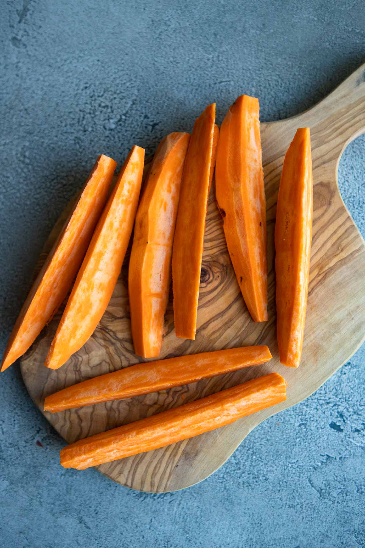 raw sliced sweet potato pieces on a cutting board