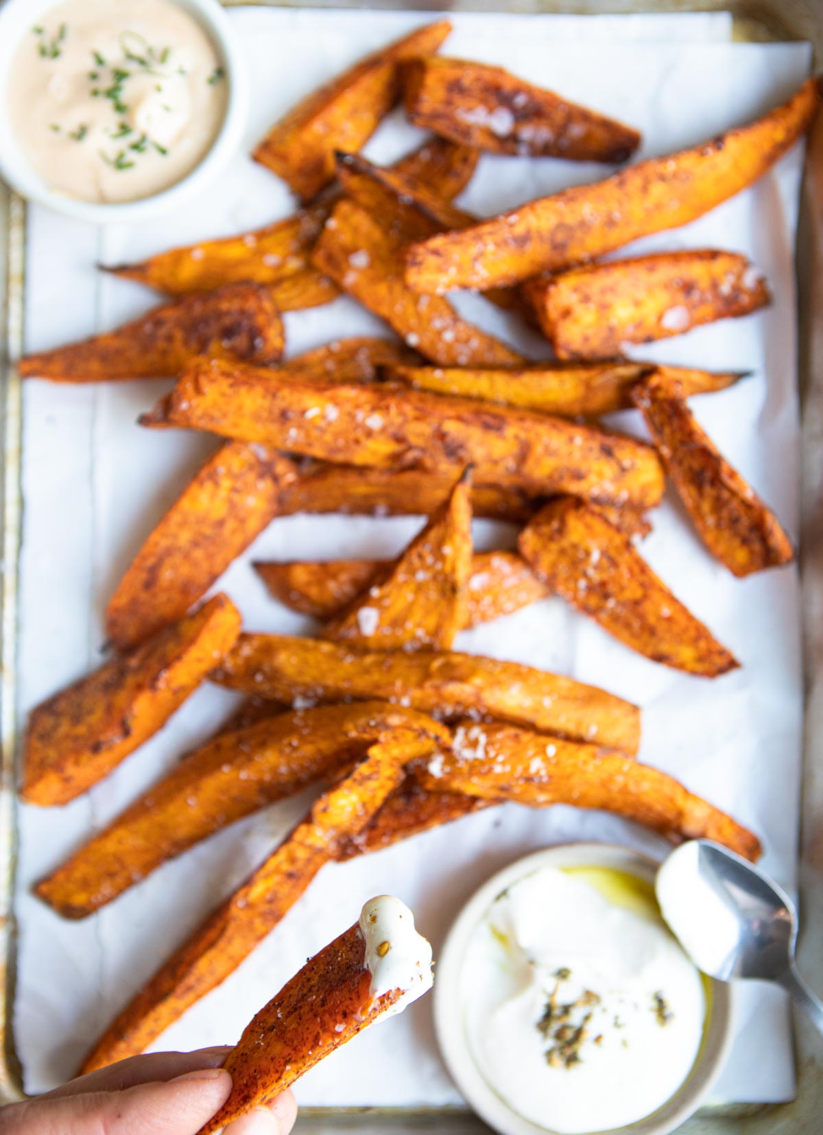 woman holding a sweet potato fry dipped in sauce