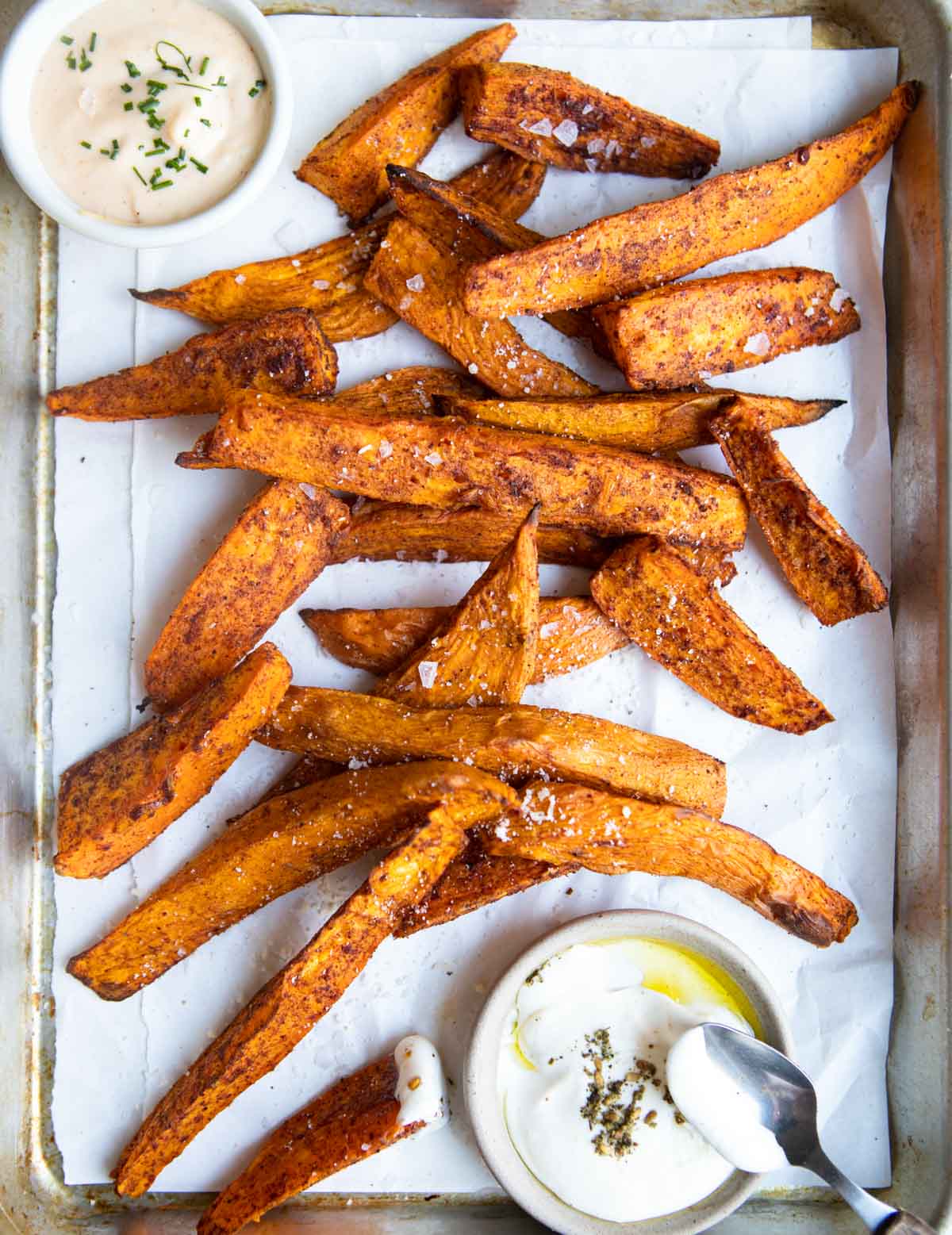 cooked sweet potato wedges on a platter sprinkled with salt, parmesan cheese and seasoning mix