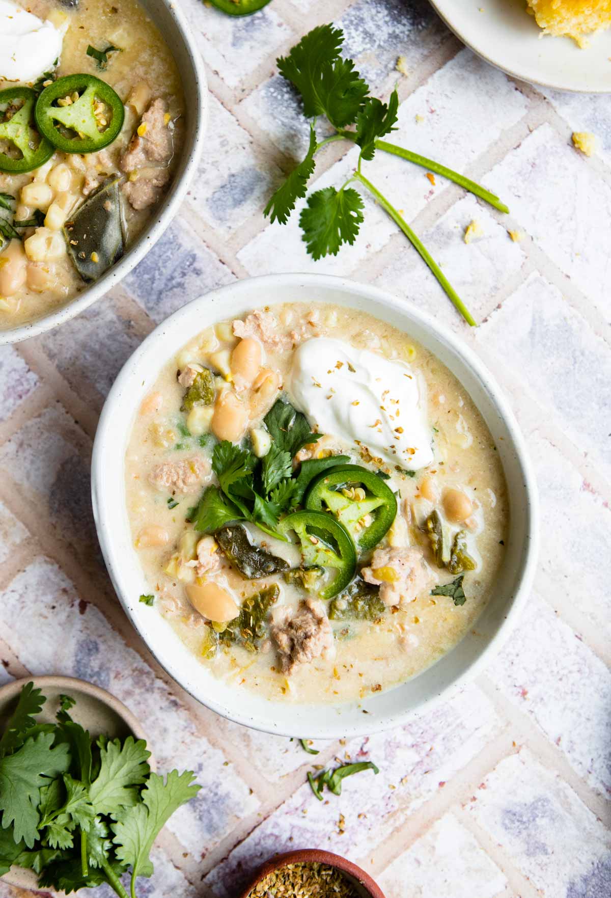 white bowl filled with chicken chili soup and garnished with cilantro and jalapenos 