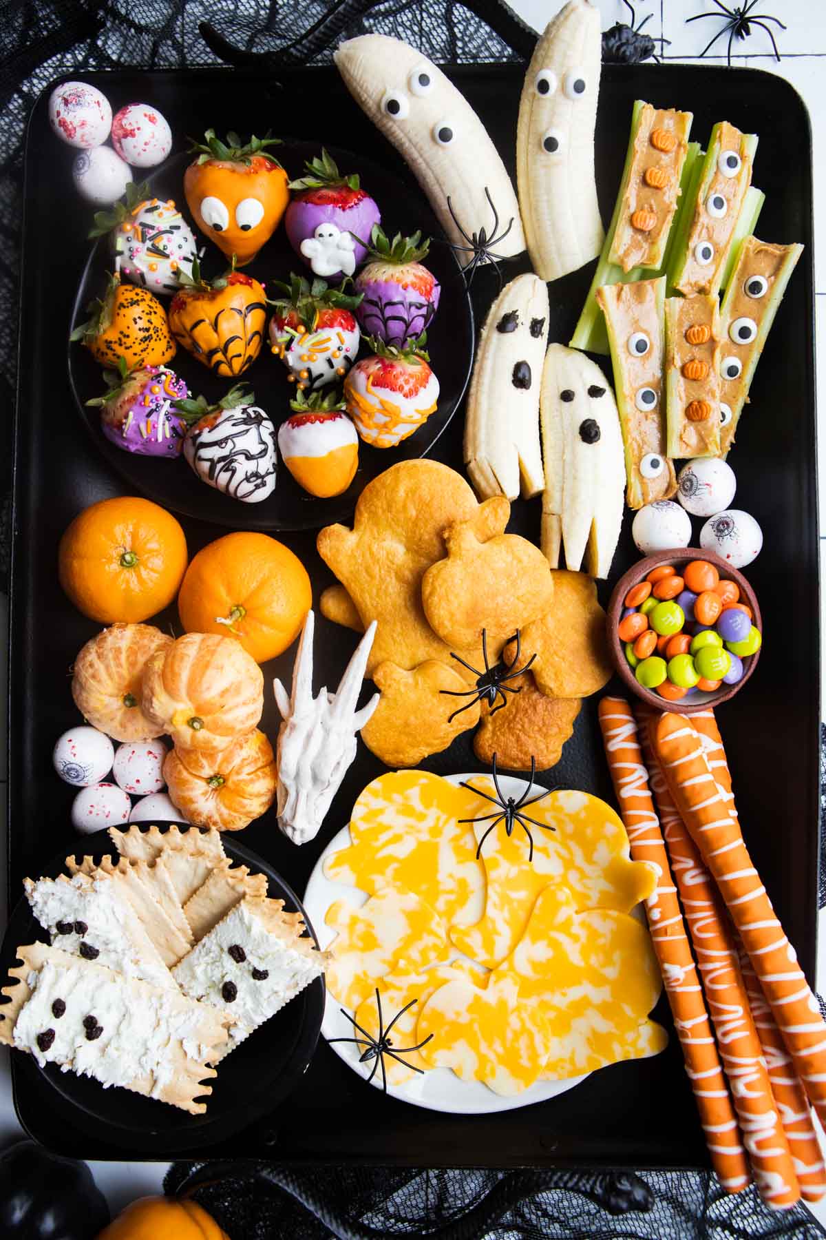 a black tray filled with Halloween treats including Halloween chocolate covered strawberries