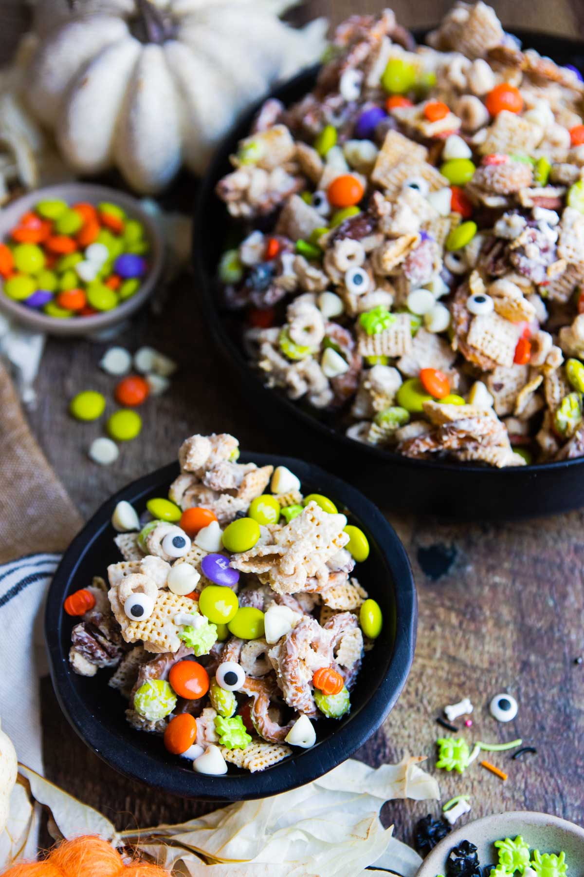 Black bowl filled with white chocolate Halloween snack mix with orange and purple M&M's and edible candy eyes