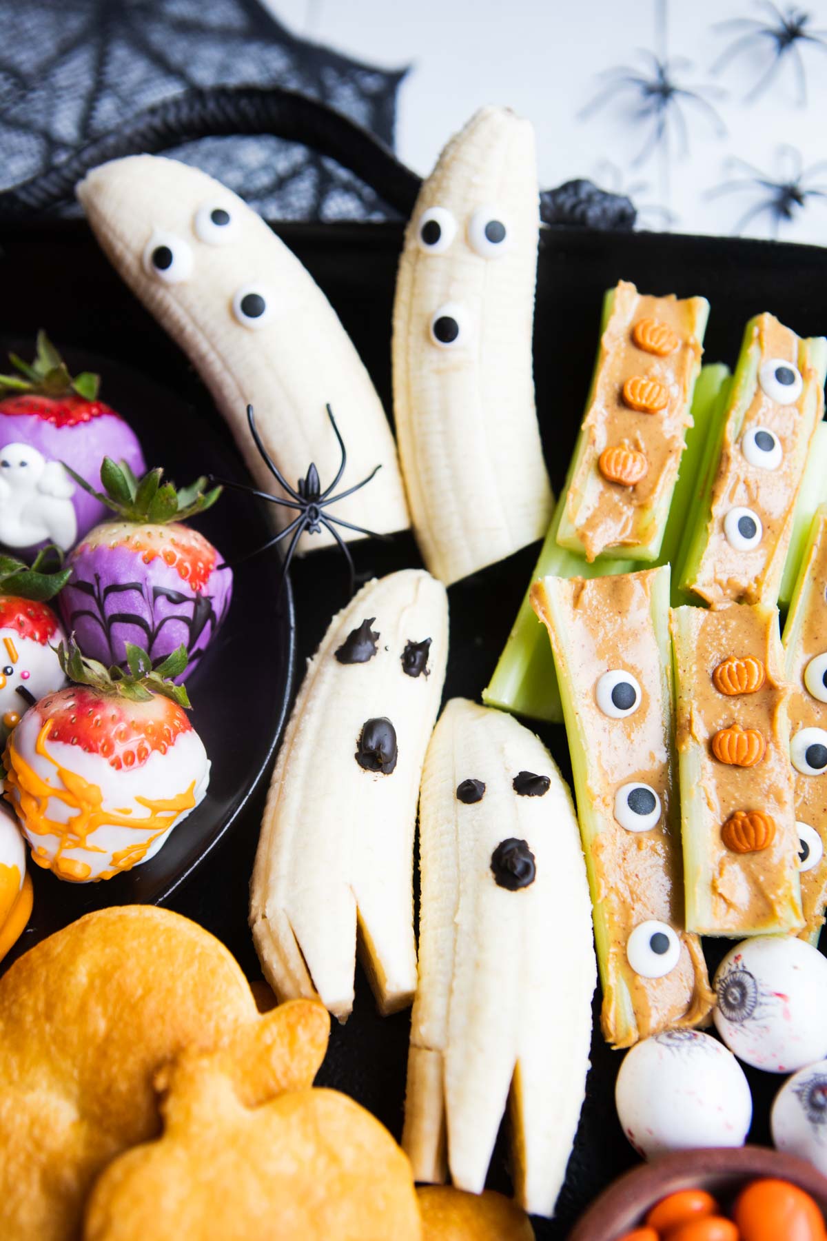 banana ghosts on a Halloween snack board surrounded by celery and strawberries