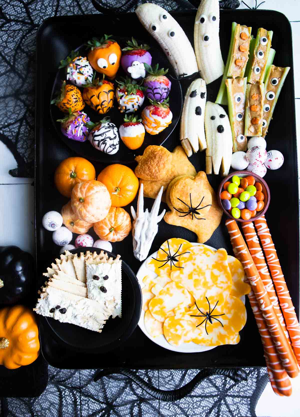 various Halloween snacks, treats and candy on a black metal tray