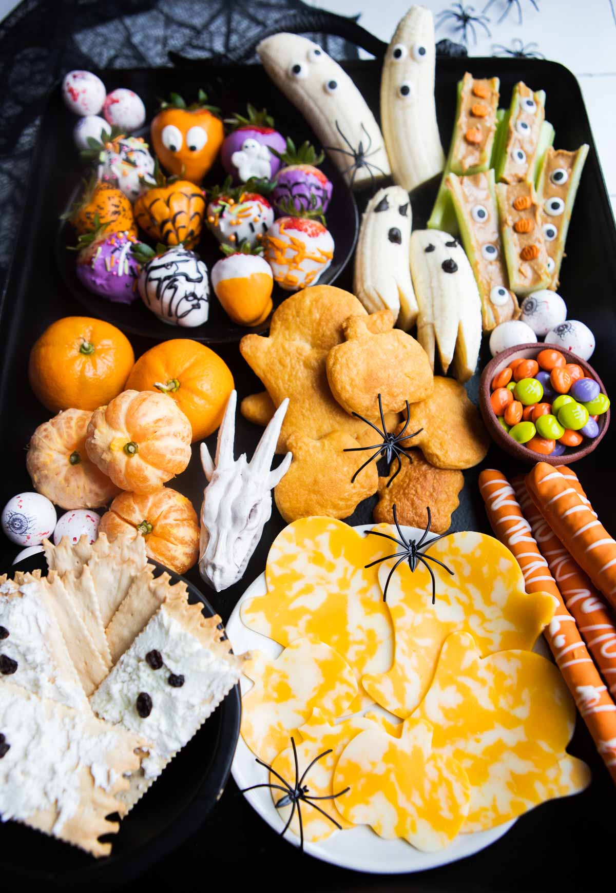 Halloween snacks and treats assembled on a black board for a halloween snack board