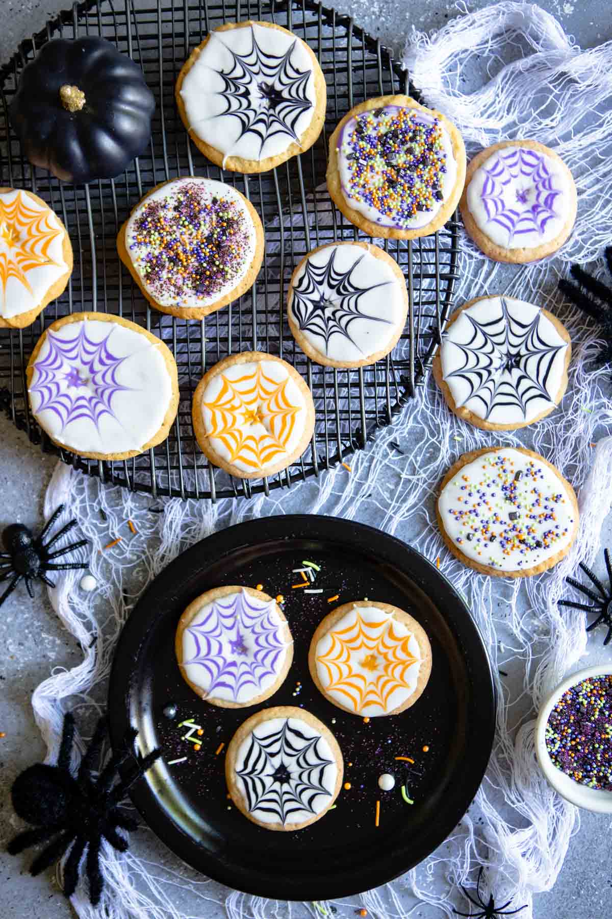 gray table filled with Halloween sugar cookies decorated as spider webs with royal icing 