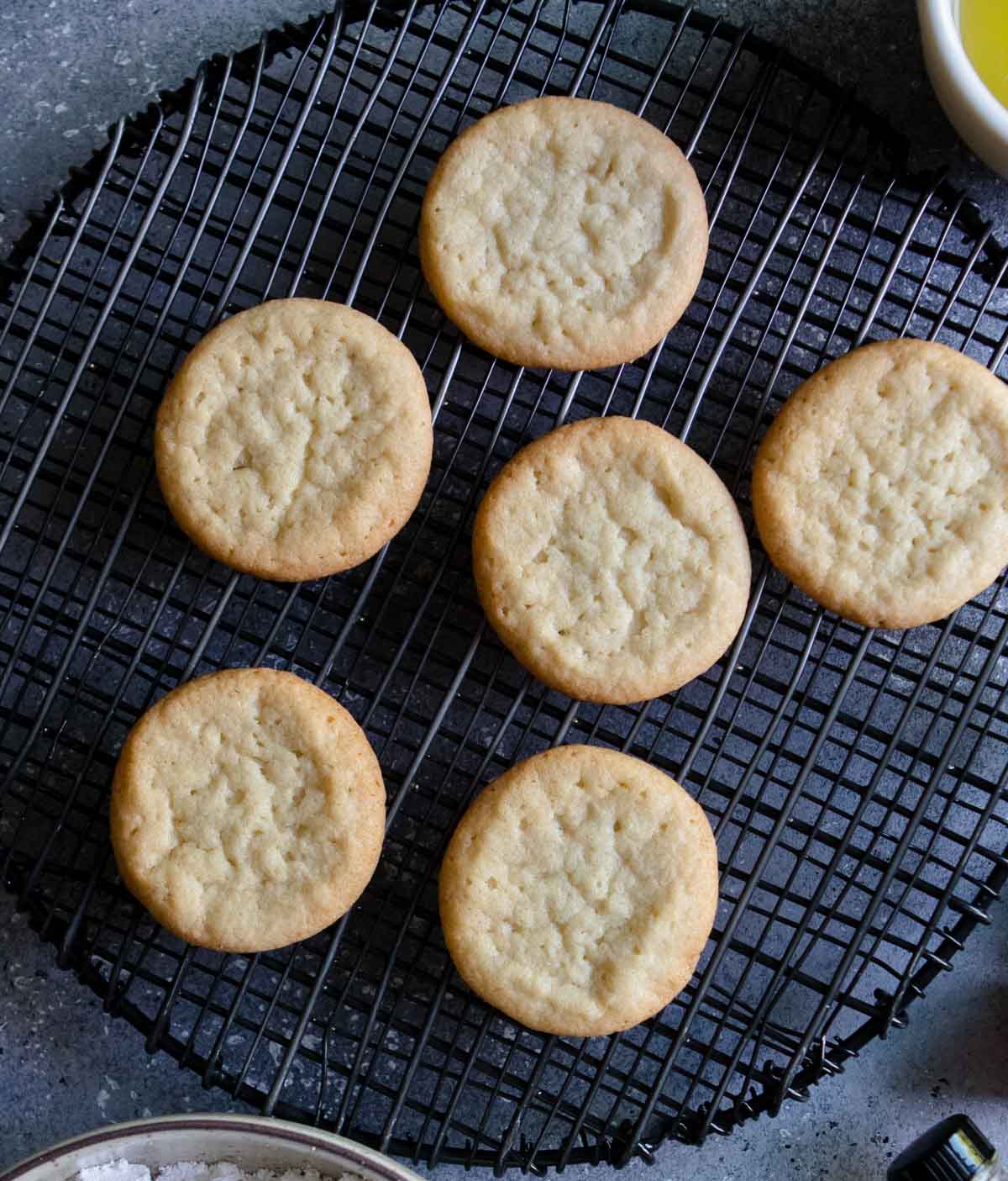 round sugar cookies baked sitting on a black wire tray