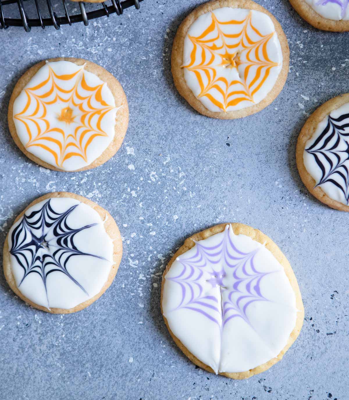 sugar cookies with white icing on them and purple lines to make spider webs