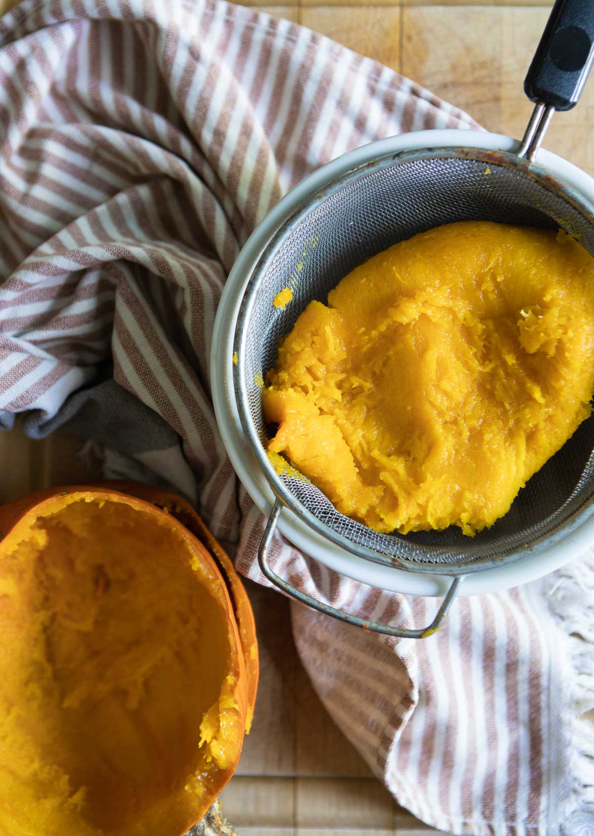 cooked instant pot pumpkin in a strainer set over a white bowl 