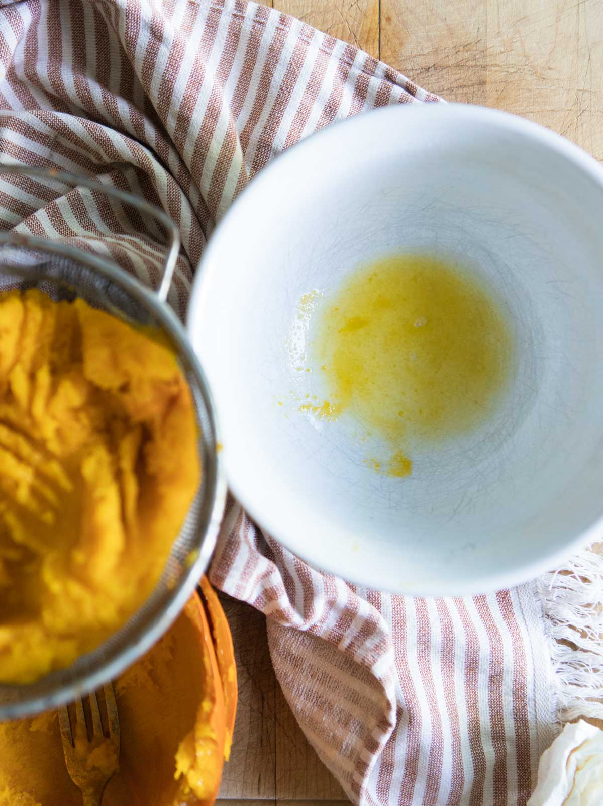 excess water drained from cooked pumpkin in a white bowl 