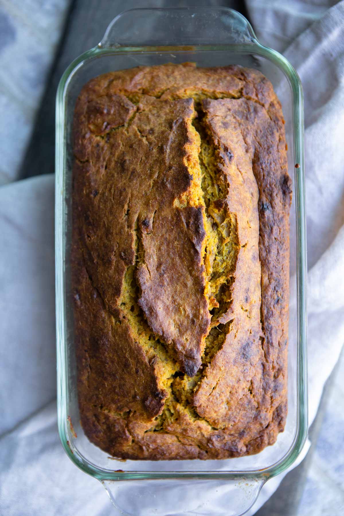 baked healthy pumpkin banana bread in a glass loaf pan cooling