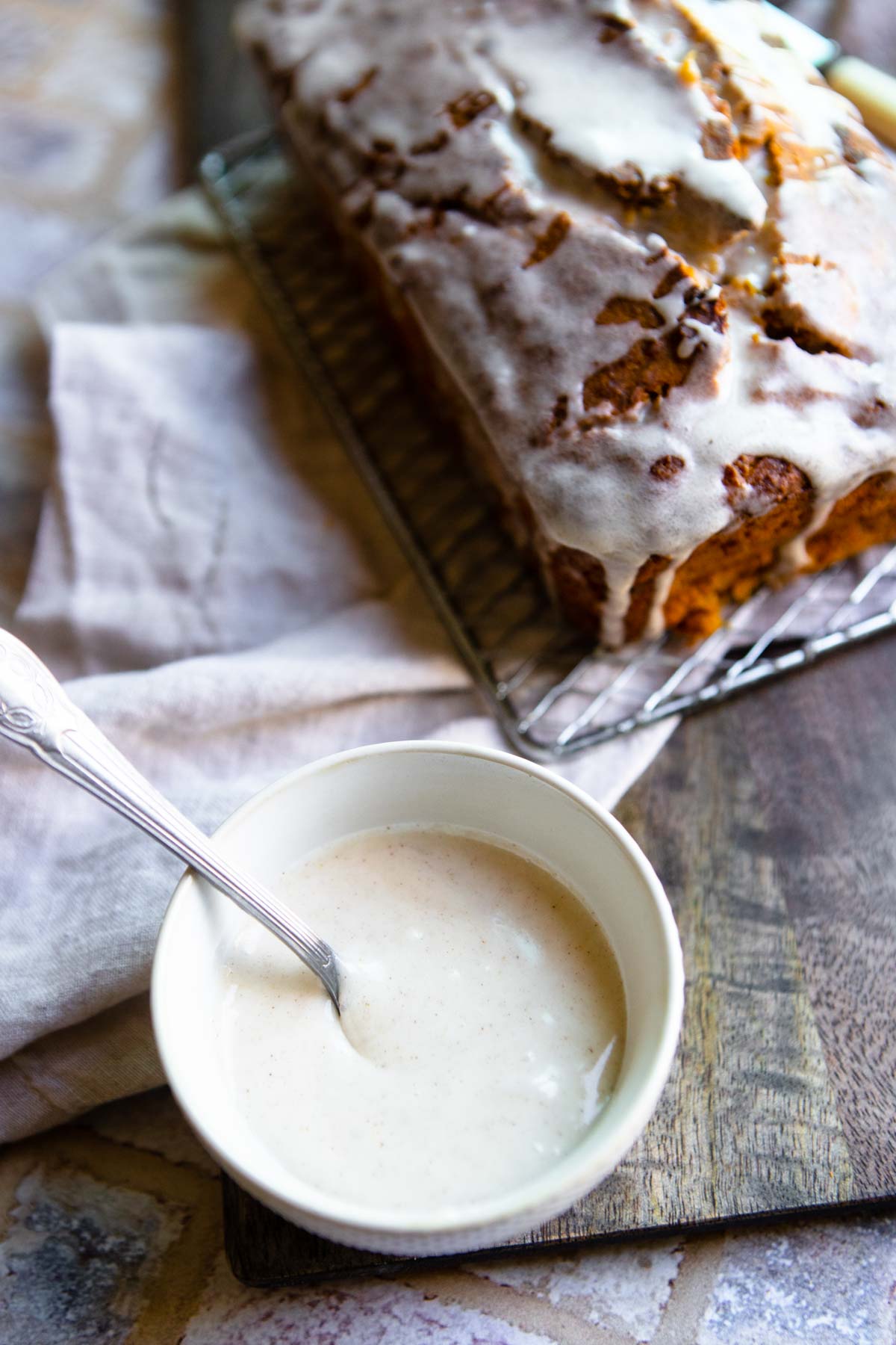 white bowl filled with pumpkin spice glaze for pumpkin bread set next to healthy pumpkin banana bread