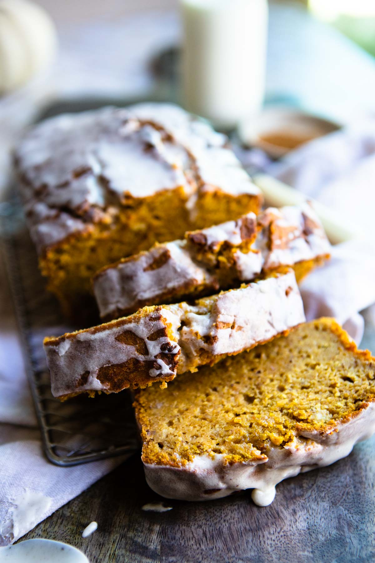 A loaf of healthy pumpkin banana bread sliced on a wire rack and covered with glaze 