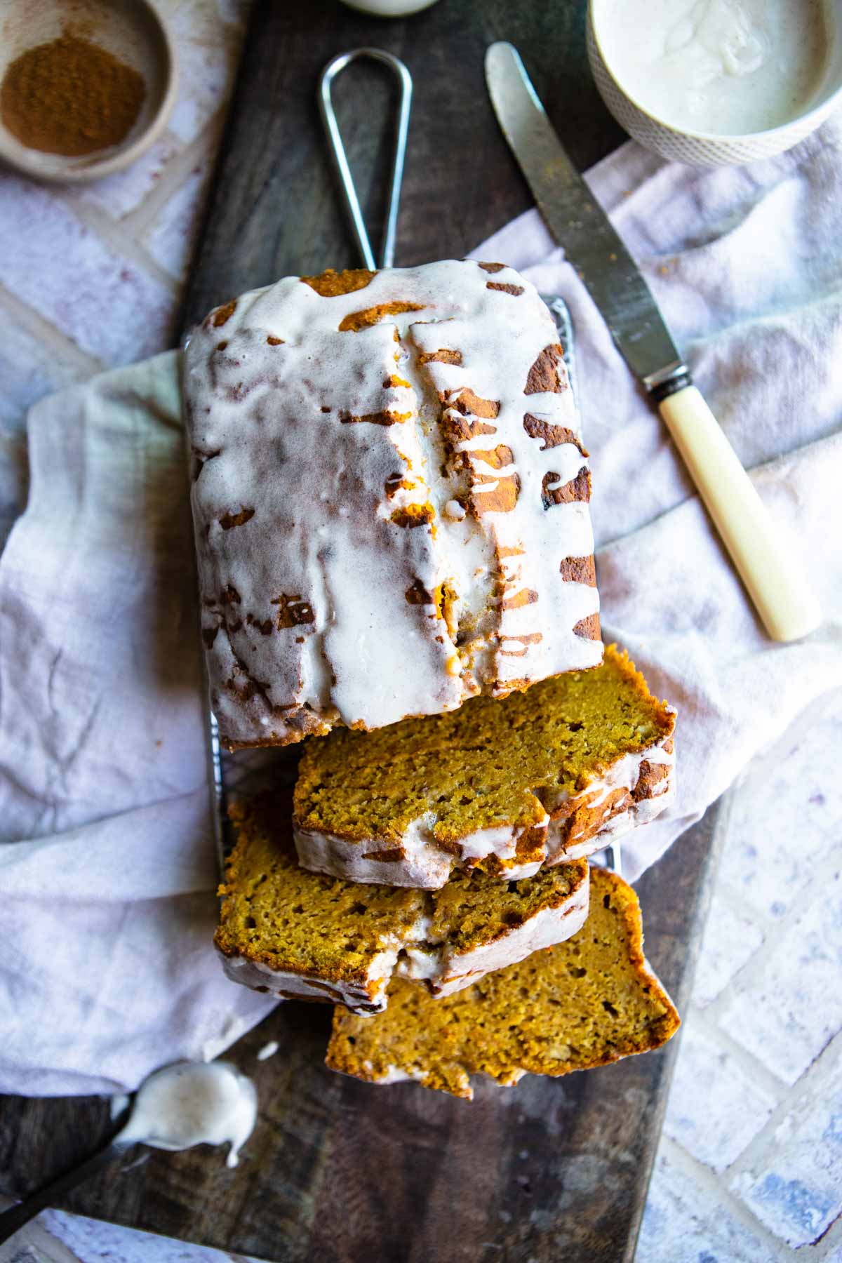 a loaf of pumpkin banana bread sliced into 4 pieces and covered in a powdered sugar bread glaze 