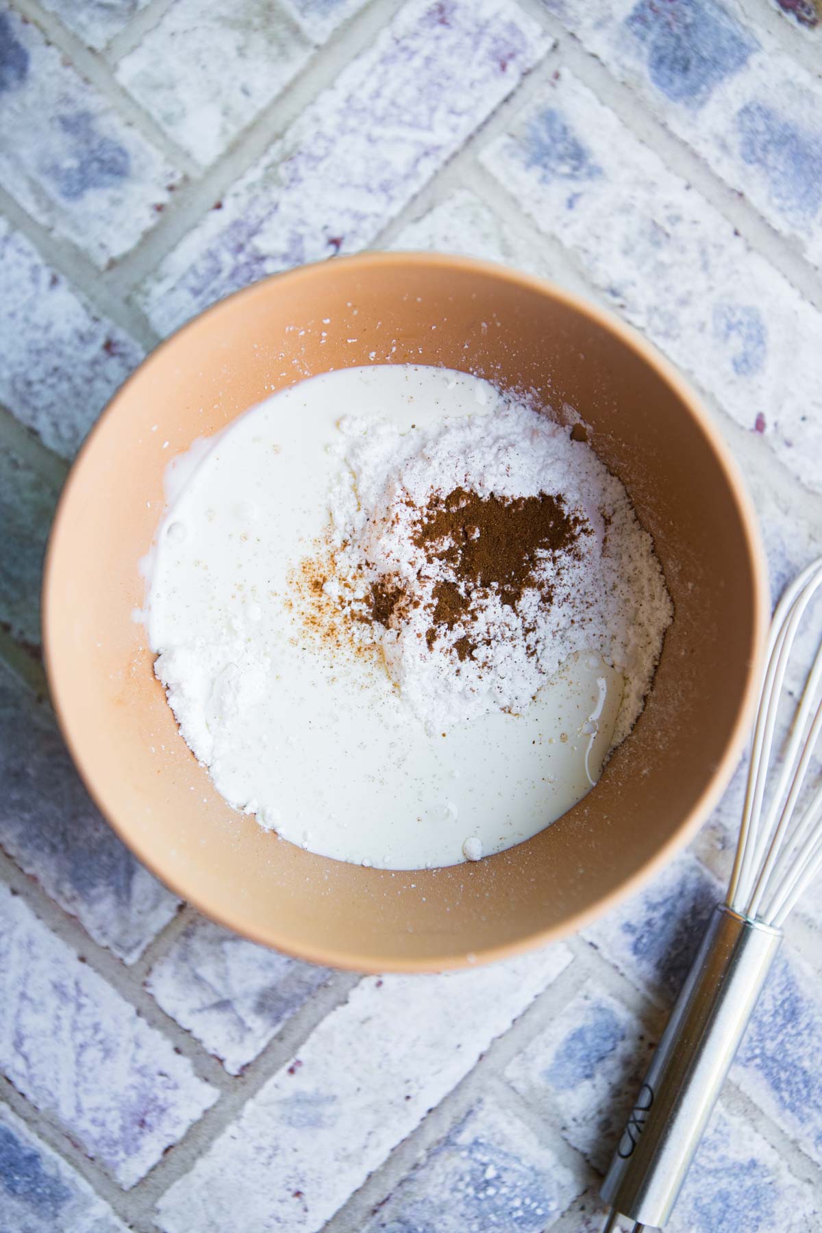 orange bowl filled with powdered sugar, pumpkin pie spice and cream to make a glaze for baked goods