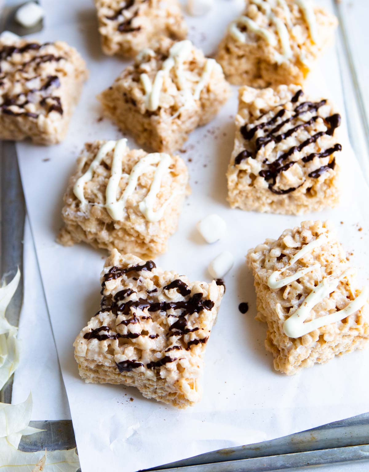 a tray of pumpkin rice krispie treats drizzled with white and dark chocolate