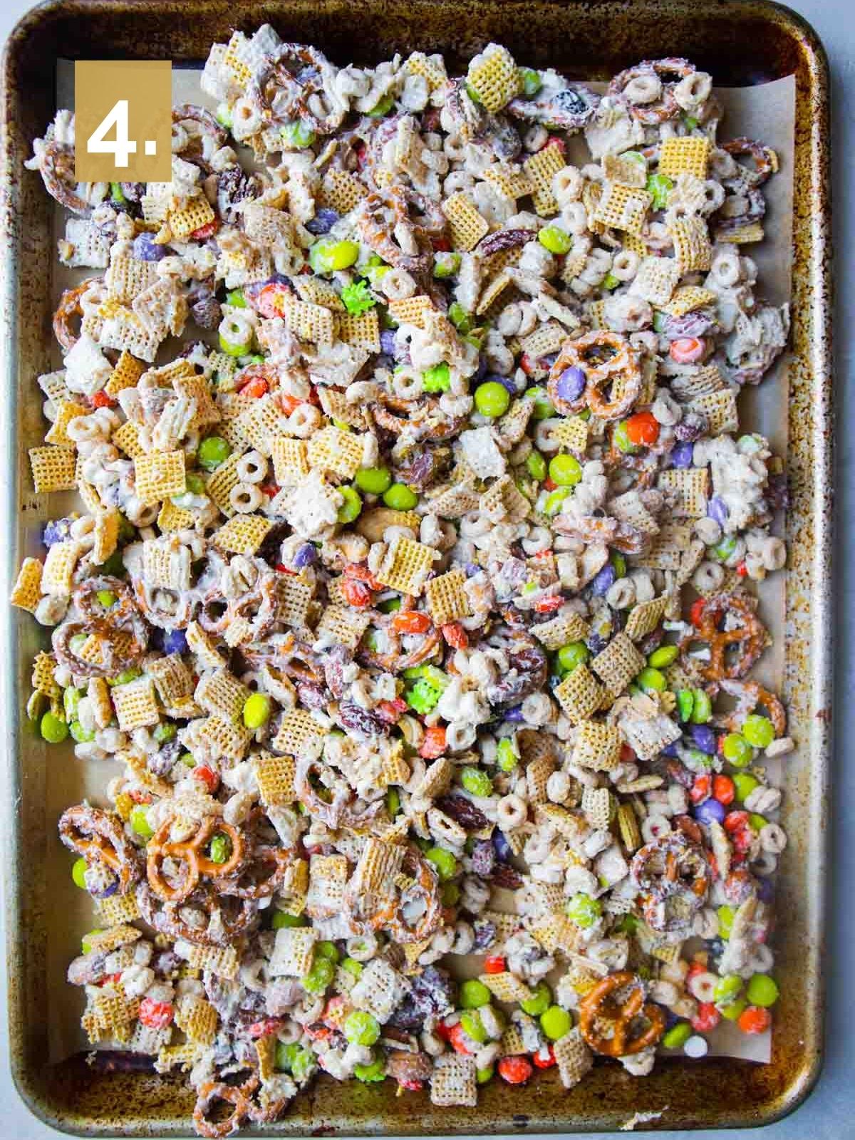white chocolate Chex mix with Halloween candy drying on a parchment lined baking tray