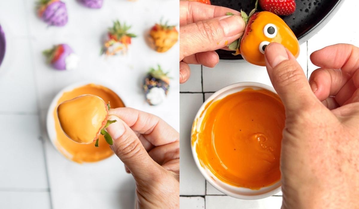 edible candy eyes being affixed to a orange chocolate covered strawberry