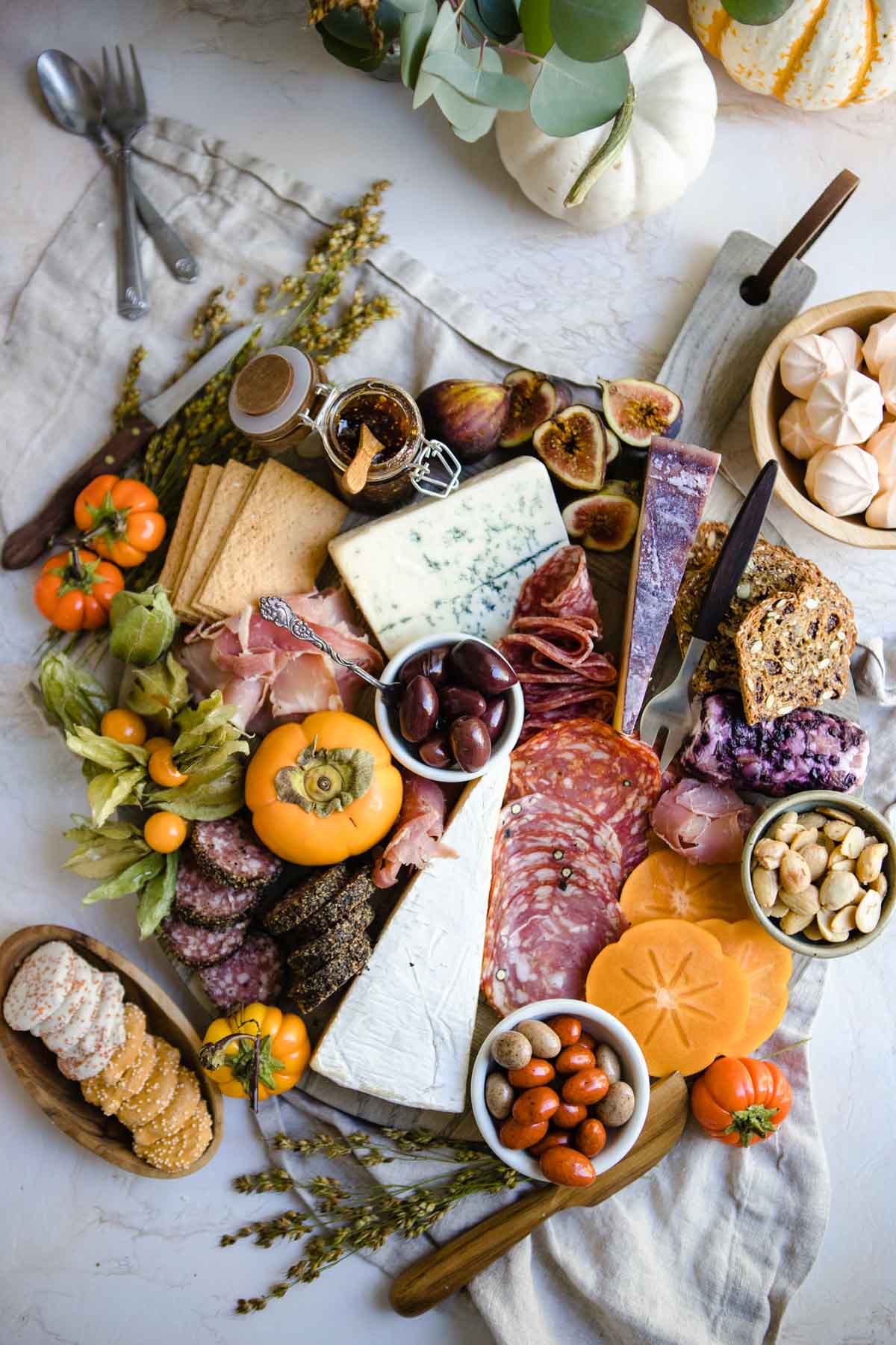 A finished fall Thanksgiving charcuterie board filled with hard and soft cheeses, a variety of cured meats and seasonal fruits 