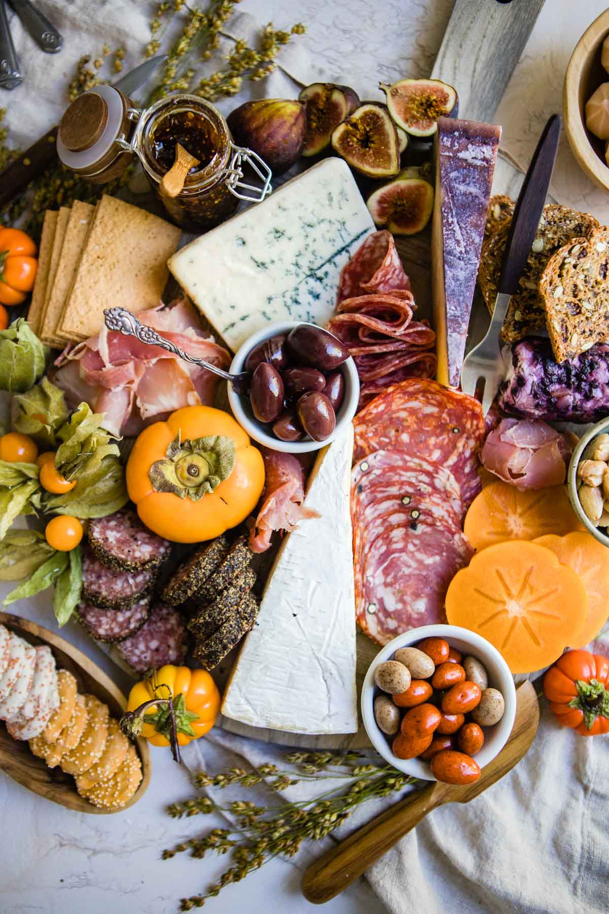 Thanksgiving charcuterie board on a round wooden board filled with persimmons, figs and goldenberries 
