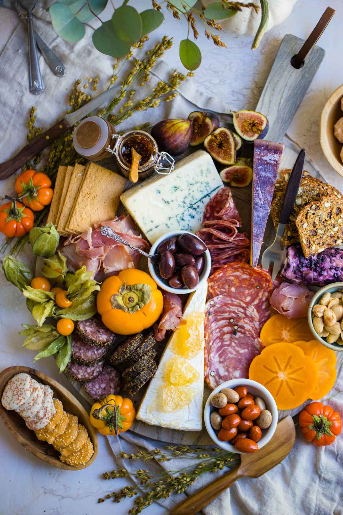 seasonal items like mini pumpkins are added to a Thanksgiving themed charcuterie board 