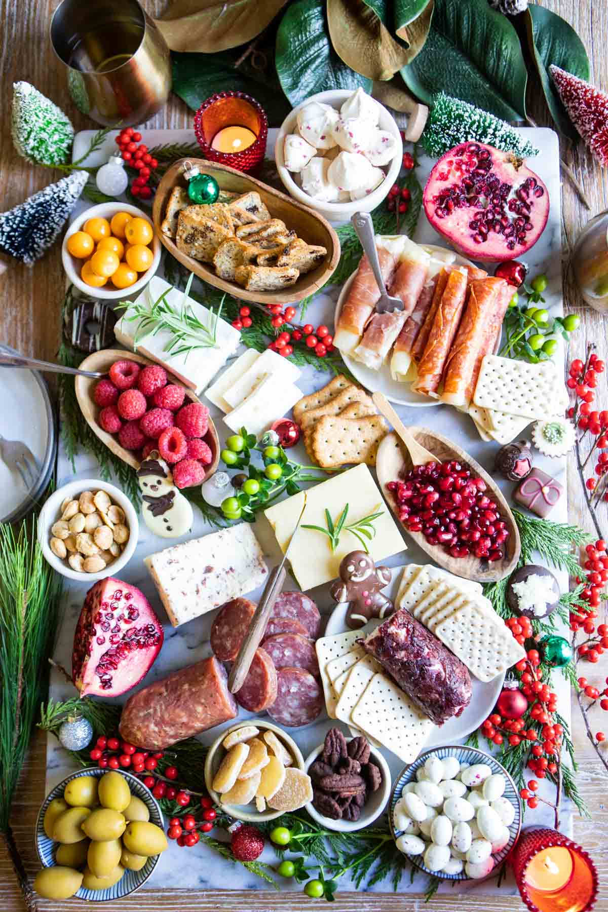 Christmas charcuterie board decorated with red and green berries and trees