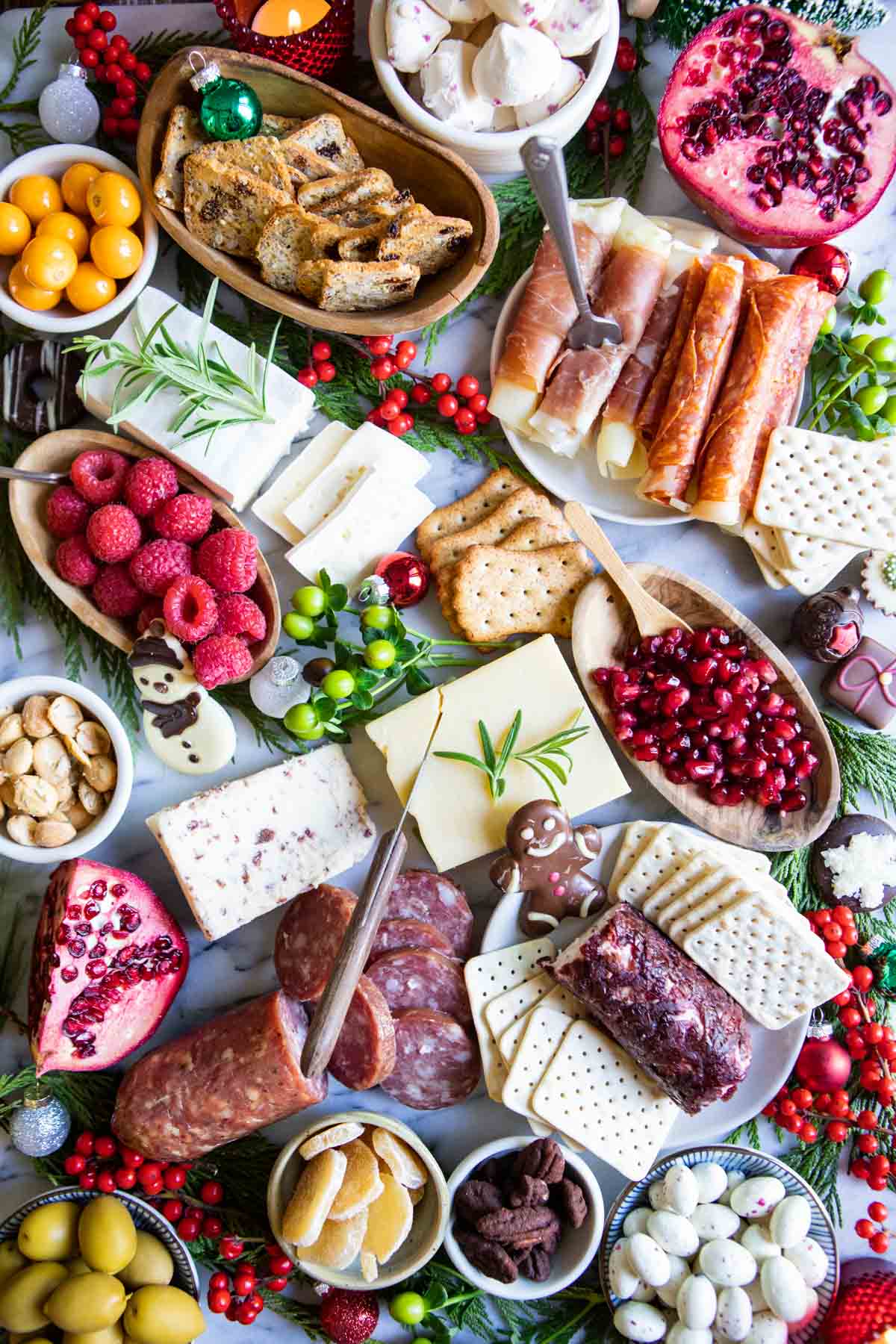 cheese, cured meats, nuts, fruit and seasonal sweets on a marble board for a holiday party
