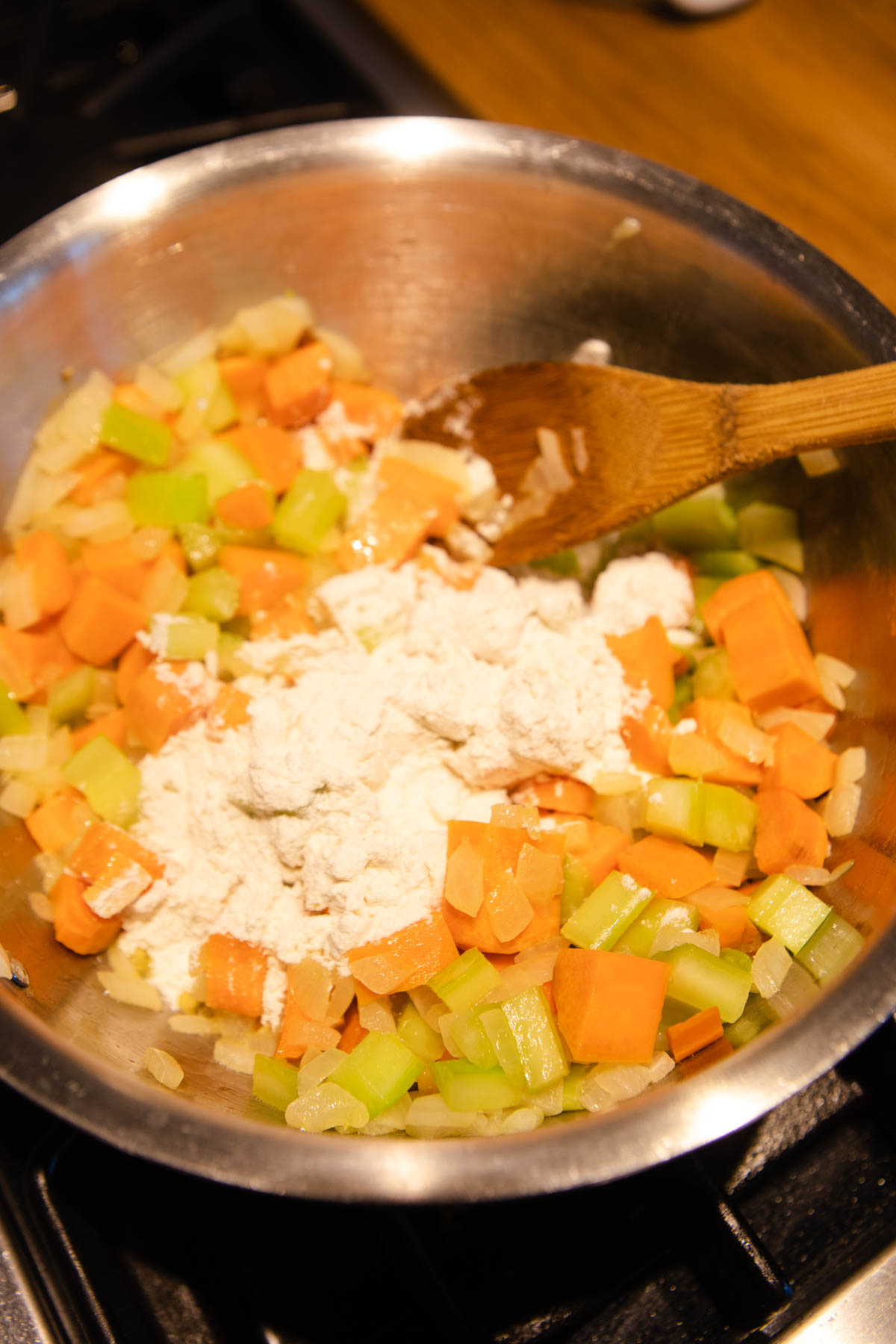 flour added to a sauce pan filled with carrots, celery and onions