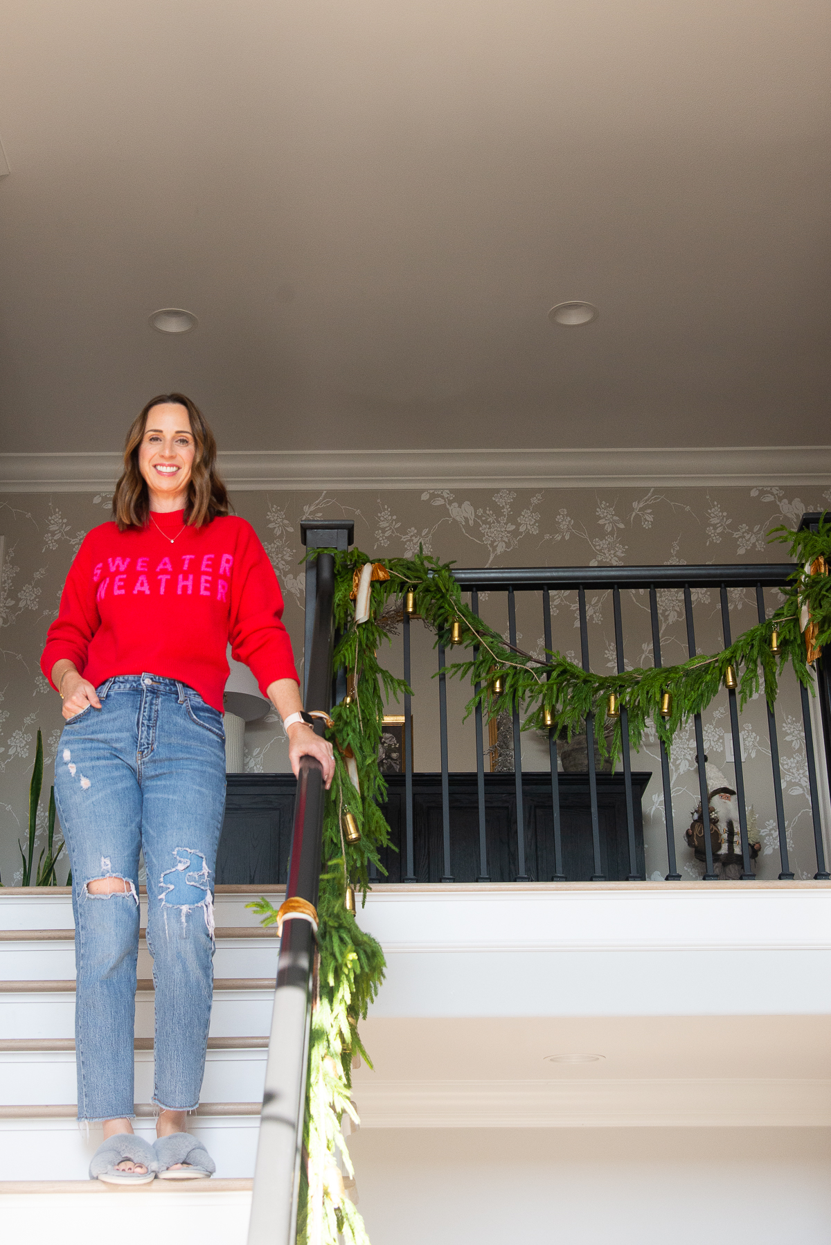 women wearing a red sweater and jeans standing on a staircase