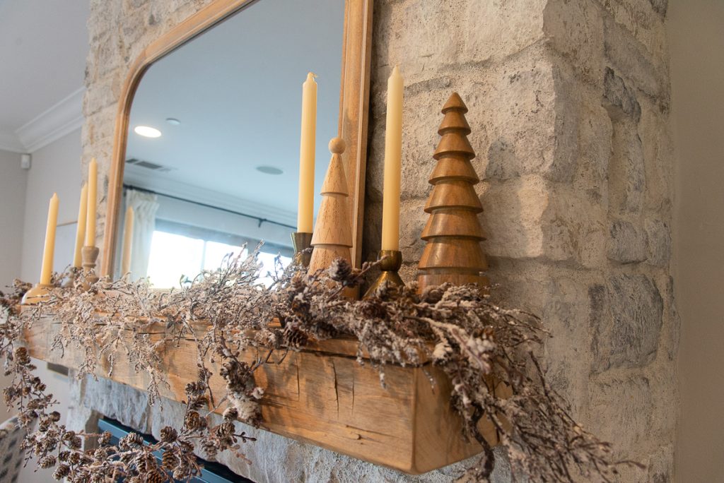wood Christmas trees and taper candles on a reclaimed wood mantel