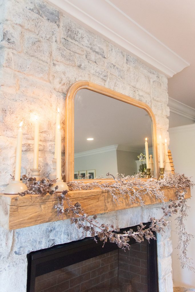 fireplace mantel decorated with garland and lit candles