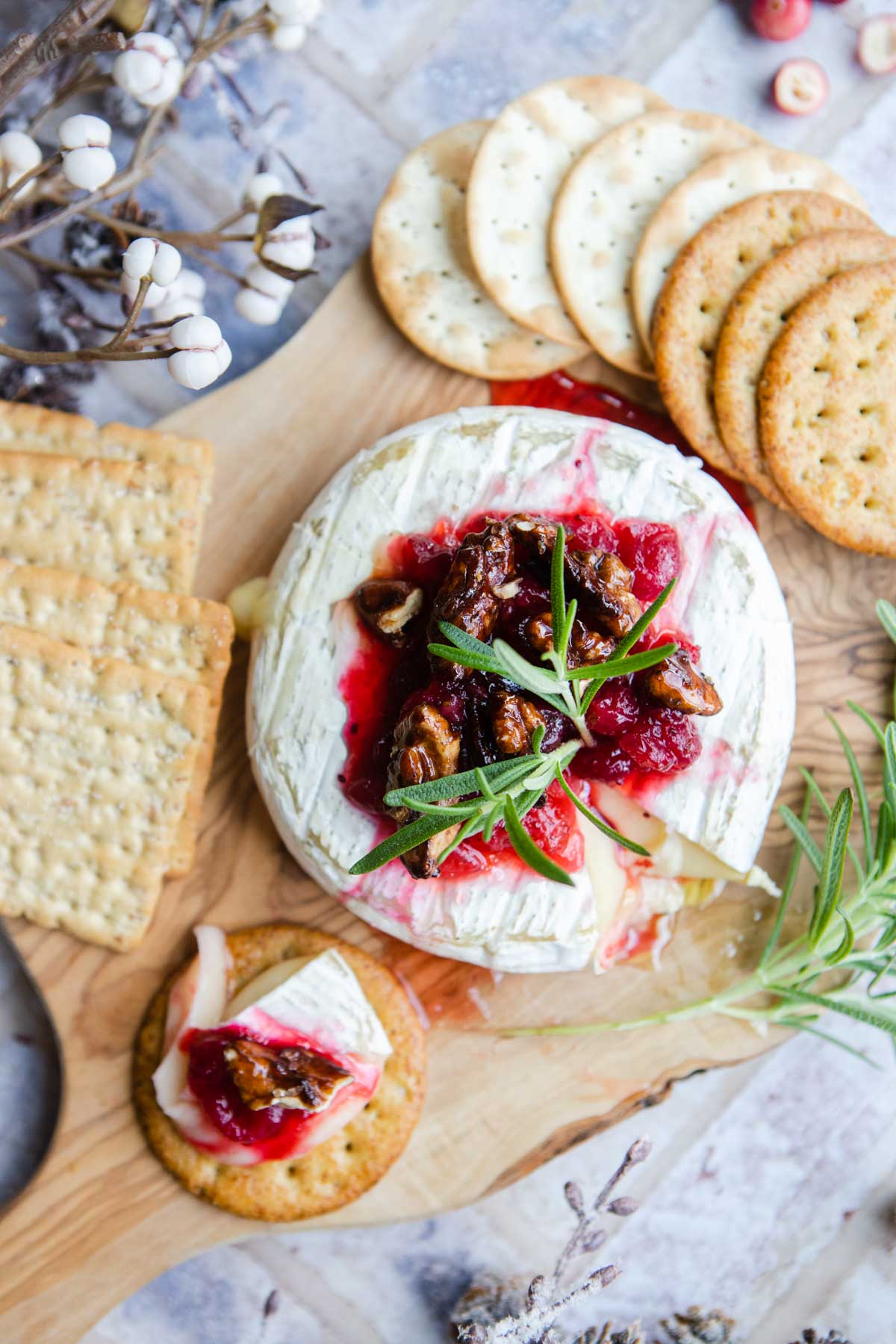 baked brie topped with jam and on a wood serving board