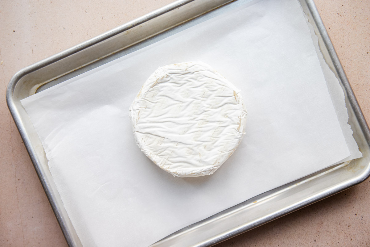 uncooked wheel of brie on a parchment lined baking sheet