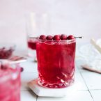cranberry gin cocktail garnished with cranberries in a cut crystal glass