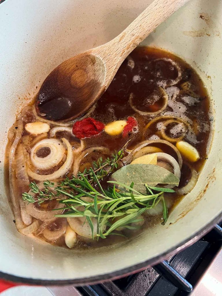 beef broth and herbs and spices simmering in a dutch oven